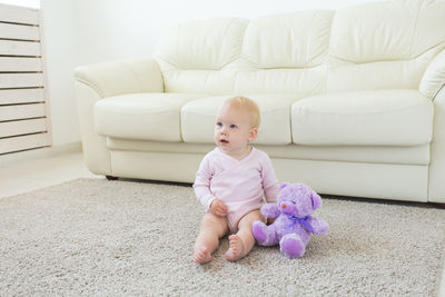 Cute baby girl sitting with toy at home