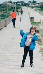 Full length portrait of woman standing on footpath