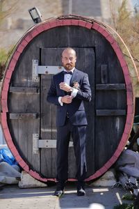 Full length of man wearing suit standing against door