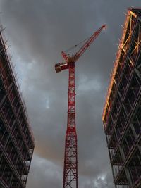 Low angle view of crane at construction site against sky