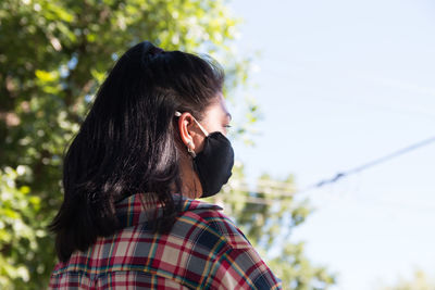 Back portrait of young woman wearing surgical face mask