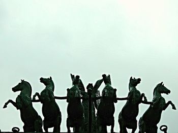 Silhouette of birds perching on wall