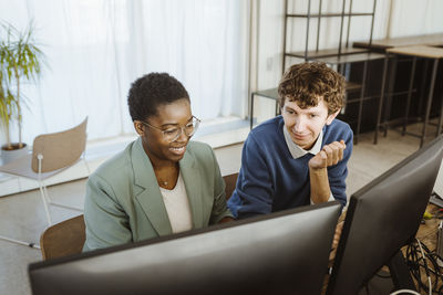 Smiling multiracial male and female programmers working on computer in creative office