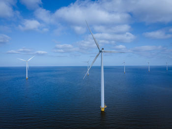 Wind turbines in sea against sky