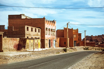 Road by buildings in city against sky