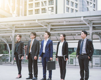 Businesspeople standing on street against buildings in city