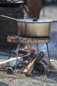 Food cooking in saucepan on metal grate at campsite