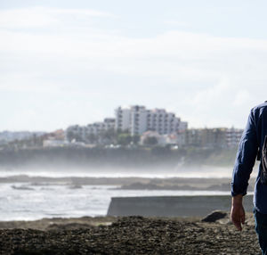 Man standing on beach against sky in city