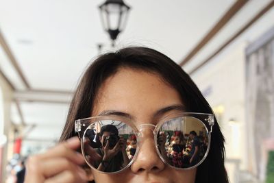 Close-up portrait of woman holding sunglasses at home