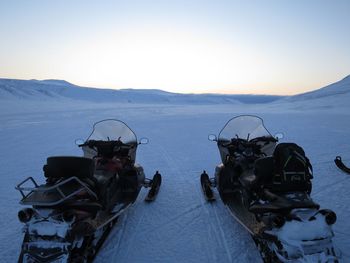 Snowmobiles on land against clear sky