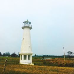 Lighthouse on landscape against clear sky