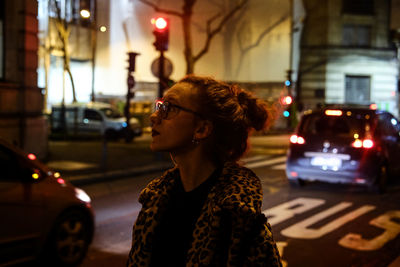 Teenage girl standing on street in city at night