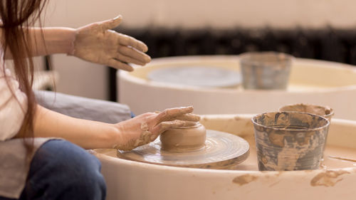 Midsection of woman making craft at table in workshop