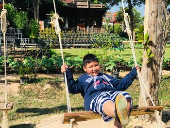 Portrait of smiling boy sitting on swing at park