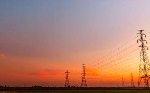 Silhouette electricity pylon on field against romantic sky at sunset. high voltage electric tower.