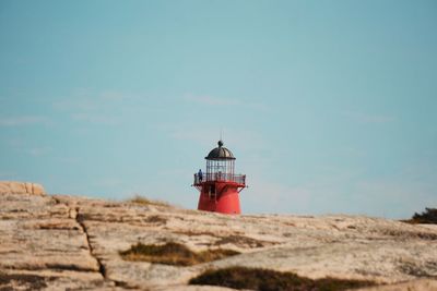 Lighthouse on rock against sky