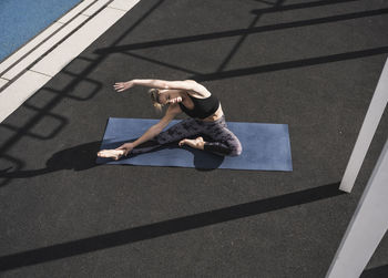 Sportswoman doing stretching exercise on yoga mat