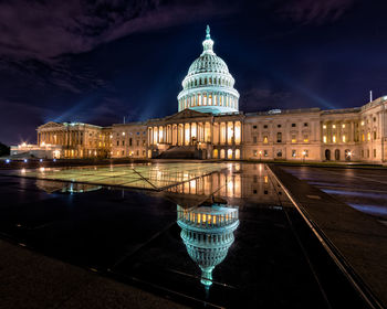 Reflection of illuminated capitol building in city at night