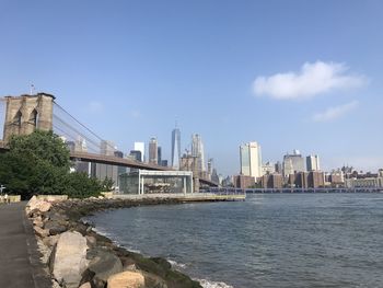 Bridge over river by buildings in city against sky