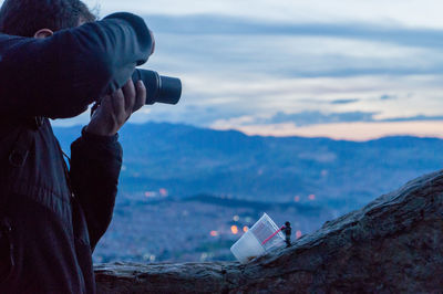 Man photographing from camera against sky during sunset