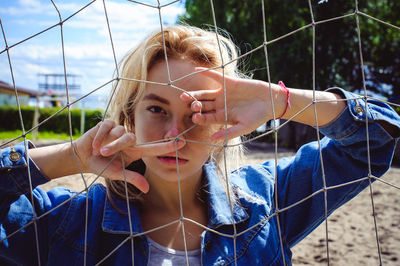 Young woman standing by net