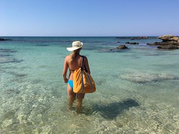 Full length of woman standing in sea against clear sky