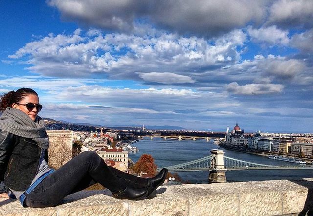 sky, lifestyles, water, leisure activity, cloud - sky, sea, casual clothing, architecture, young adult, built structure, sitting, person, building exterior, standing, relaxation, railing, rear view, young women