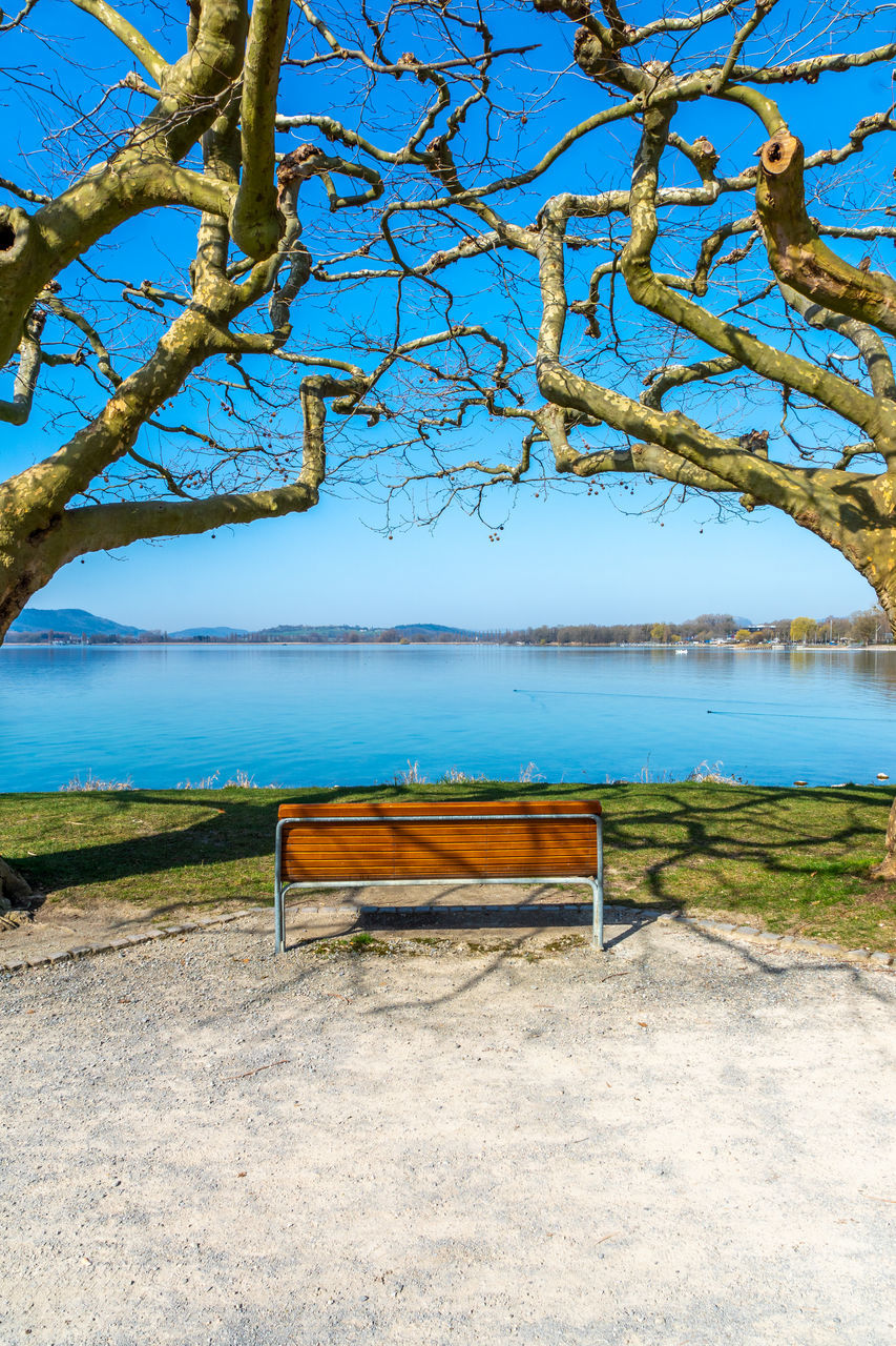 EMPTY BENCHES ON BEACH AGAINST BLUE SKY