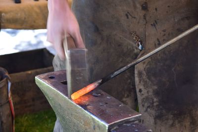 Midsection of worker working on metal at factory