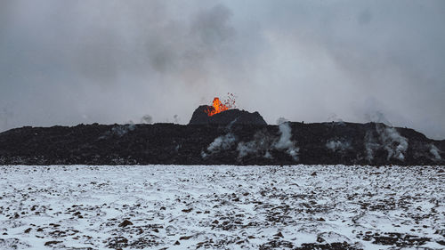 Person on snow covered land against sky