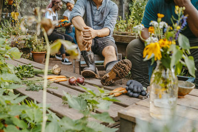 Male and female farmers talking while sitting in community garden