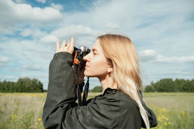 Side view of man photographing with camera against sky