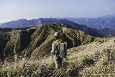 Rear view of woman standing on field against mountain