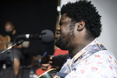 Male musician playing guitar while singing in microphone at studio