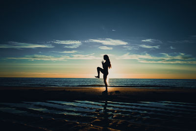 Silhouette man standing on beach against sky during sunset