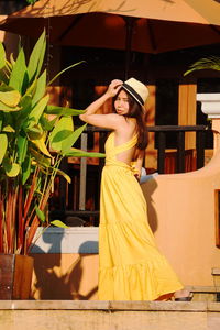 Side view of woman wearing hat standing in front of house