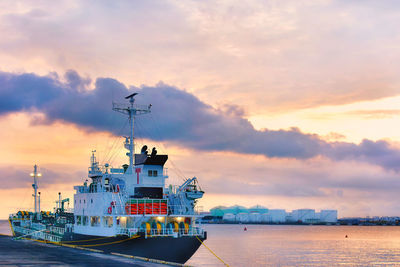 Cargo ship in sea against sky during sunset