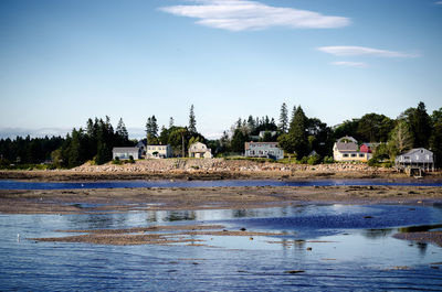 Houses by lake against clear blue sky