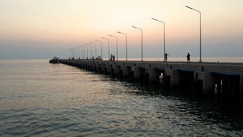 Pier over sea against sky during sunset