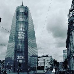 Low angle view of skyscrapers against cloudy sky