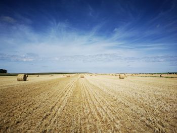 Hay bales on field against sky