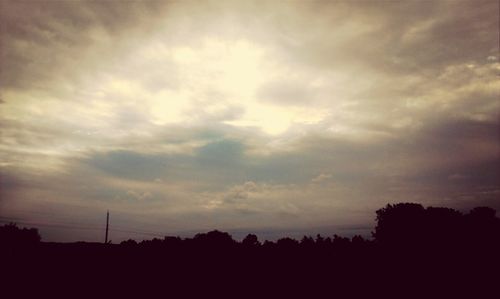 Silhouette of trees against cloudy sky