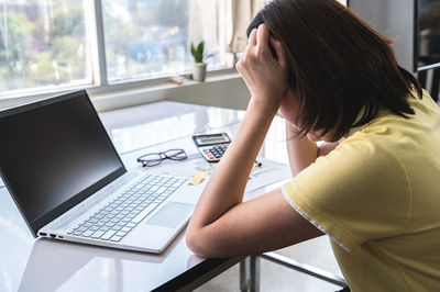 Midsection of woman using mobile phone while sitting on table