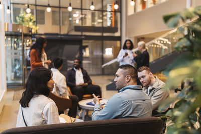 Multiracial male and female entrepreneurs discussing business strategies while sitting in lobby at convention center