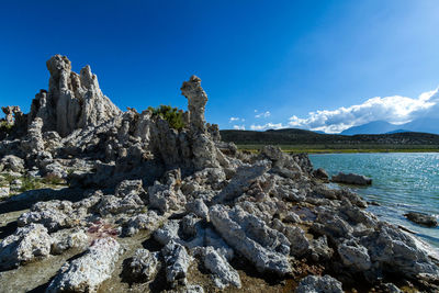 Scenic view of rocks against sea and blue sky