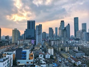 Modern buildings in city against sky during sunset