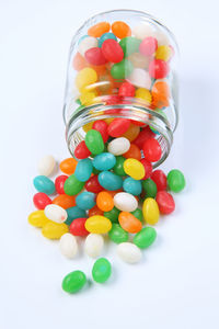 Multi colored candies spilling from jar against white background