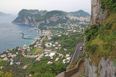 City by mountains at coastline against sky