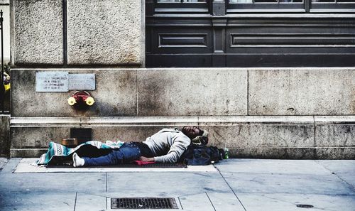 Man sitting on sidewalk in city
