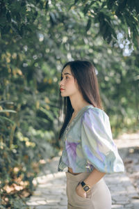 Young woman standing against trees